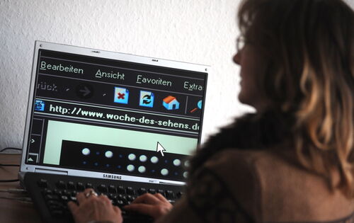 Eine Frau sitzt an einem Computer und scrollt durch eine Webseite. Ihre Darstellung ist invertiert.