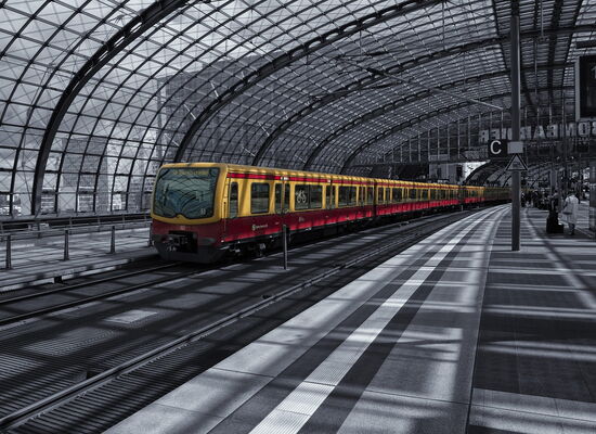 Ein menschenleerer Bahnsteig mit weißem Leitstreifen, eingefasst von zwei dunklen Kontraststreifen.